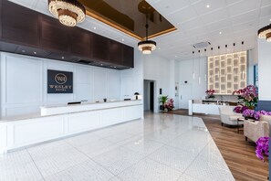 A modern hotel lobby with a reception desk, a large chandelier, and a decorative wall with a grid pattern. - Wesley Hotel (Bukit Mertajam)
