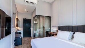 Una habitación de hotel moderna con una cama grande, un escritorio y zona de ducha.