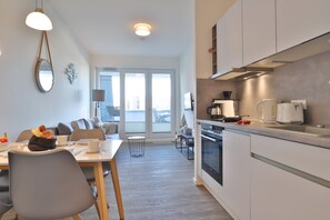 A modern kitchen with a dining area, a large window, and a view of the city. - Hafenspitze App. 09, Deutschland (Wismar)