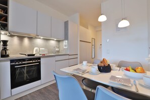 A modern kitchen with a dining area, featuring a Siemens oven, a coffee machine, and a dining table with chairs. - Hafenspitze App. 09, Deutschland (Wismar)