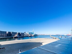 A harbor with a large ship docked, buildings, and a clear blue sky.
