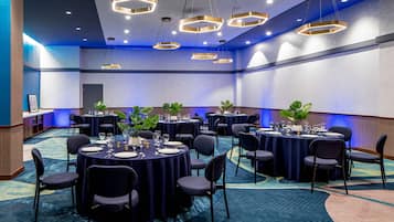 Un salón de conferencias con mesas redondas, sillas e iluminación moderna.