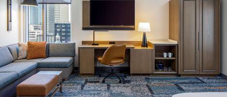 Une chambre d’hôtel moderne équipée d’un canapé, d’un bureau, d’une chaise et d’une armoire.