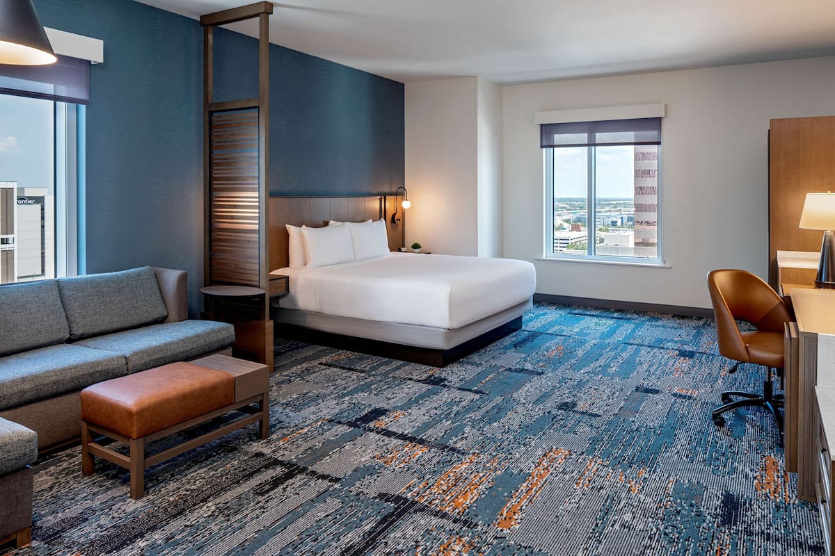 Ein Hotelzimmer mit einem Bett, einer Couch, einem Schreibtisch und einem Sessel.