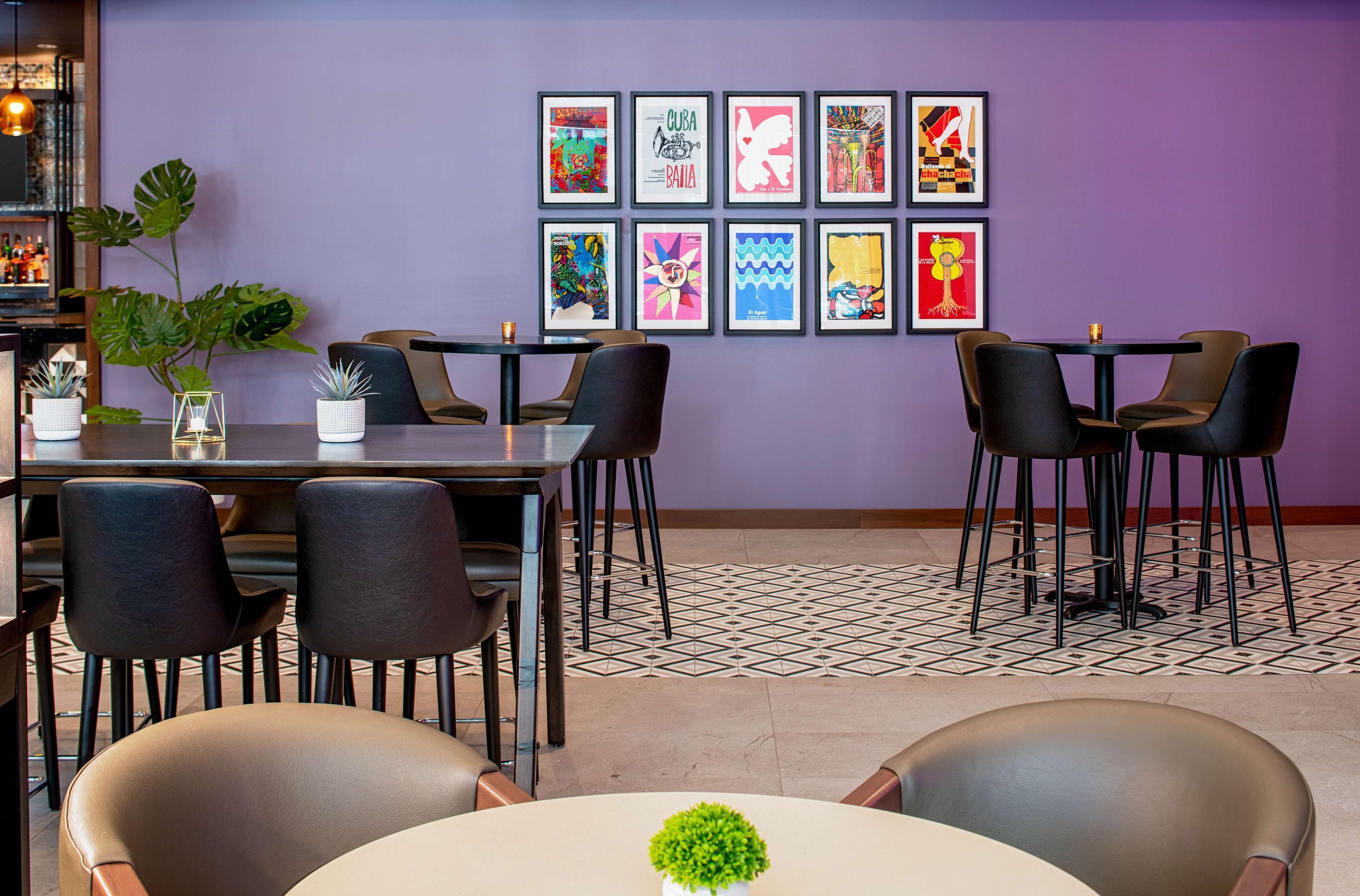 Un restaurant avec des tables et des chaises, une plante en pot et un mur orné de tableaux.