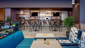 Un moderno espacio de bar con asientos, una barra y una variedad de botellas.