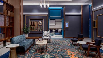 Un hall d’entrée moderne avec un canapé, des fauteuils, une table basse et un tapis à motifs.