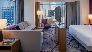 Habitación de hotel con sofá, sillón, escritorio y cama.