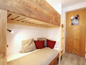 Ein Stockbett unter einer Holzzieldecke mit einer Tür, die ein kleines Fenster hat.