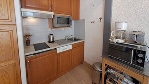 Una cocina compacta con armarios de madera, un microondas, una cafetera y un tostador.
