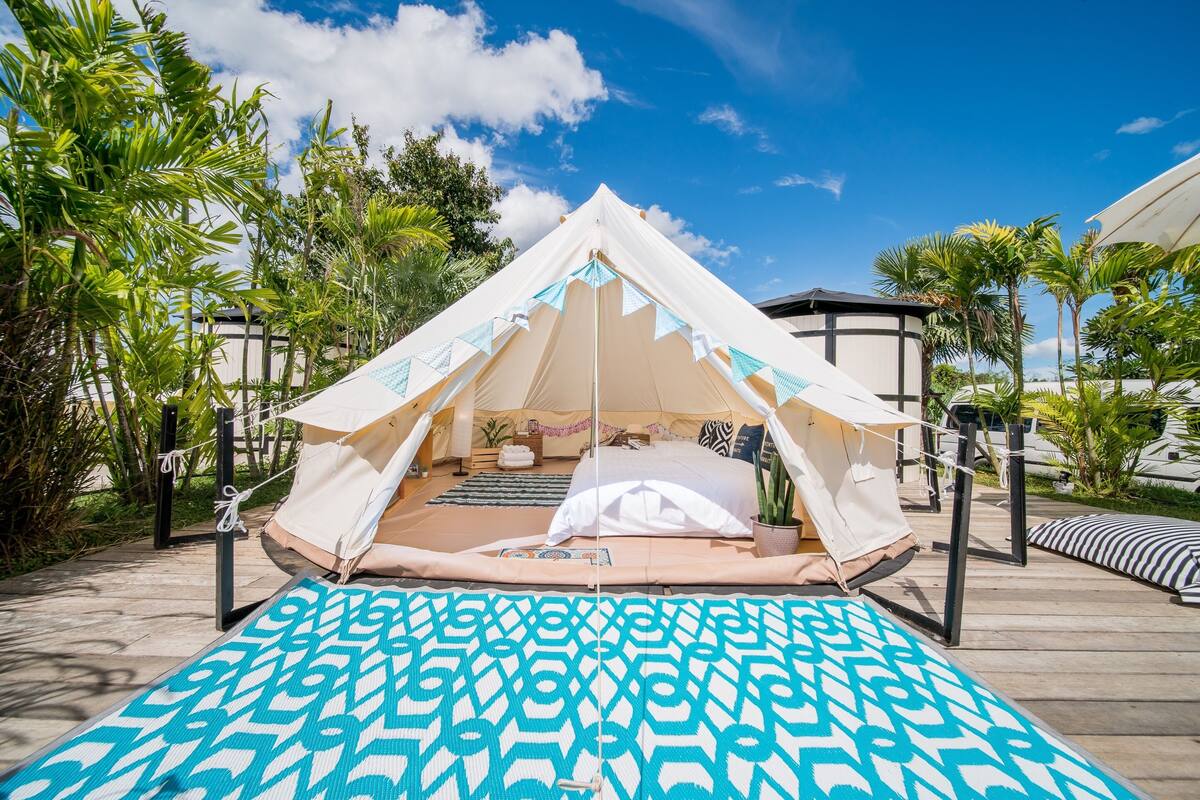 Eine Zelthütte mit einem Bett, Kissen und einer gemusterten Schlafmatte.