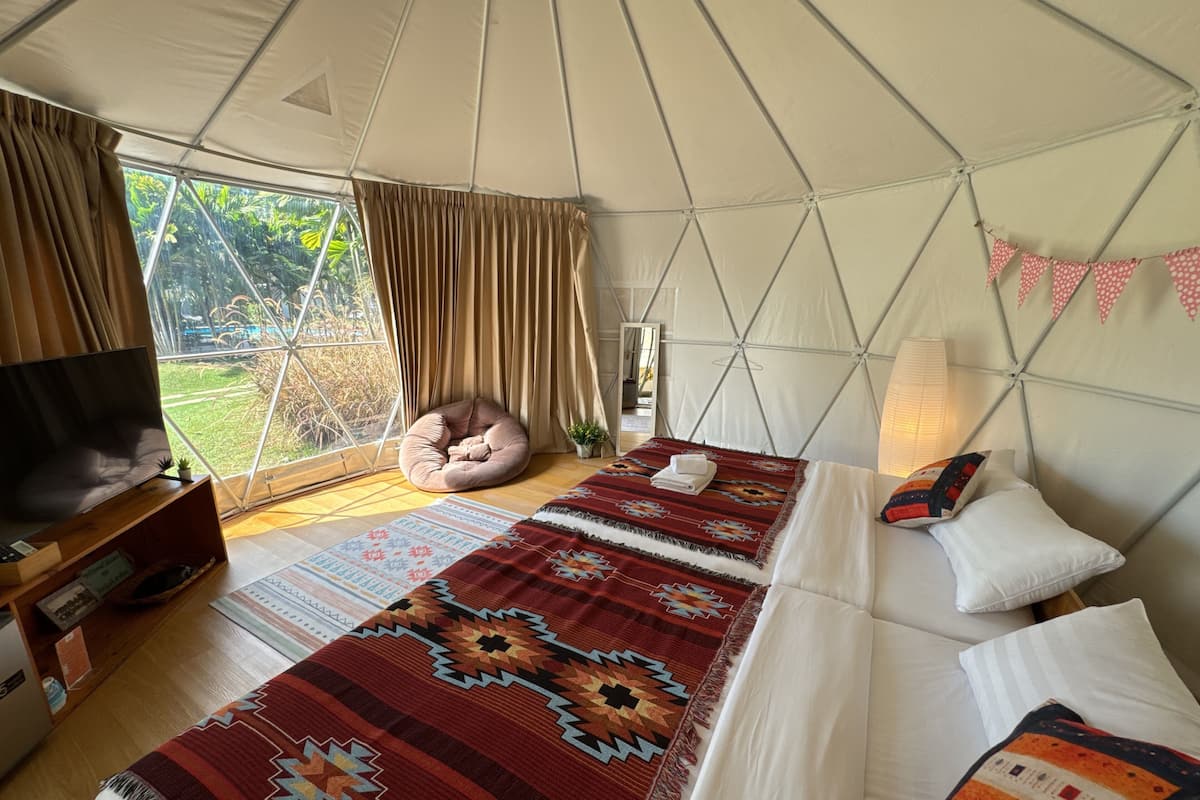 Eine Zelthütte mit zwei Betten, einem Fernseher und einem Sitzsack.