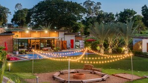 A modern house with a pool, outdoor seating, and string lights.