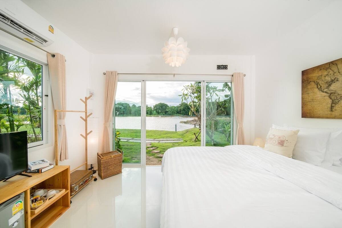 Ein Schlafzimmer mit einem großen Bett, einem Fernseher und Seeblick durch eine Schiebetür.