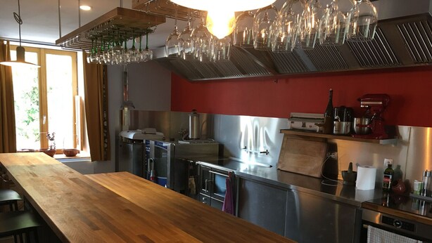 Une cuisine moderne avec un plan de travail en bois, des appareils en acier inoxydable et des verres à vin suspendus.