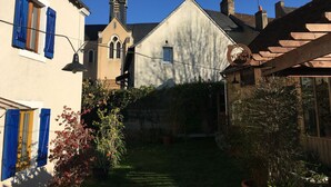 Une ruelle étroite, avec le clocher d’une église, un bâtiment blanc doté d’un toit à deux versants et une structure en bois sur laquelle est apposée une enseigne.