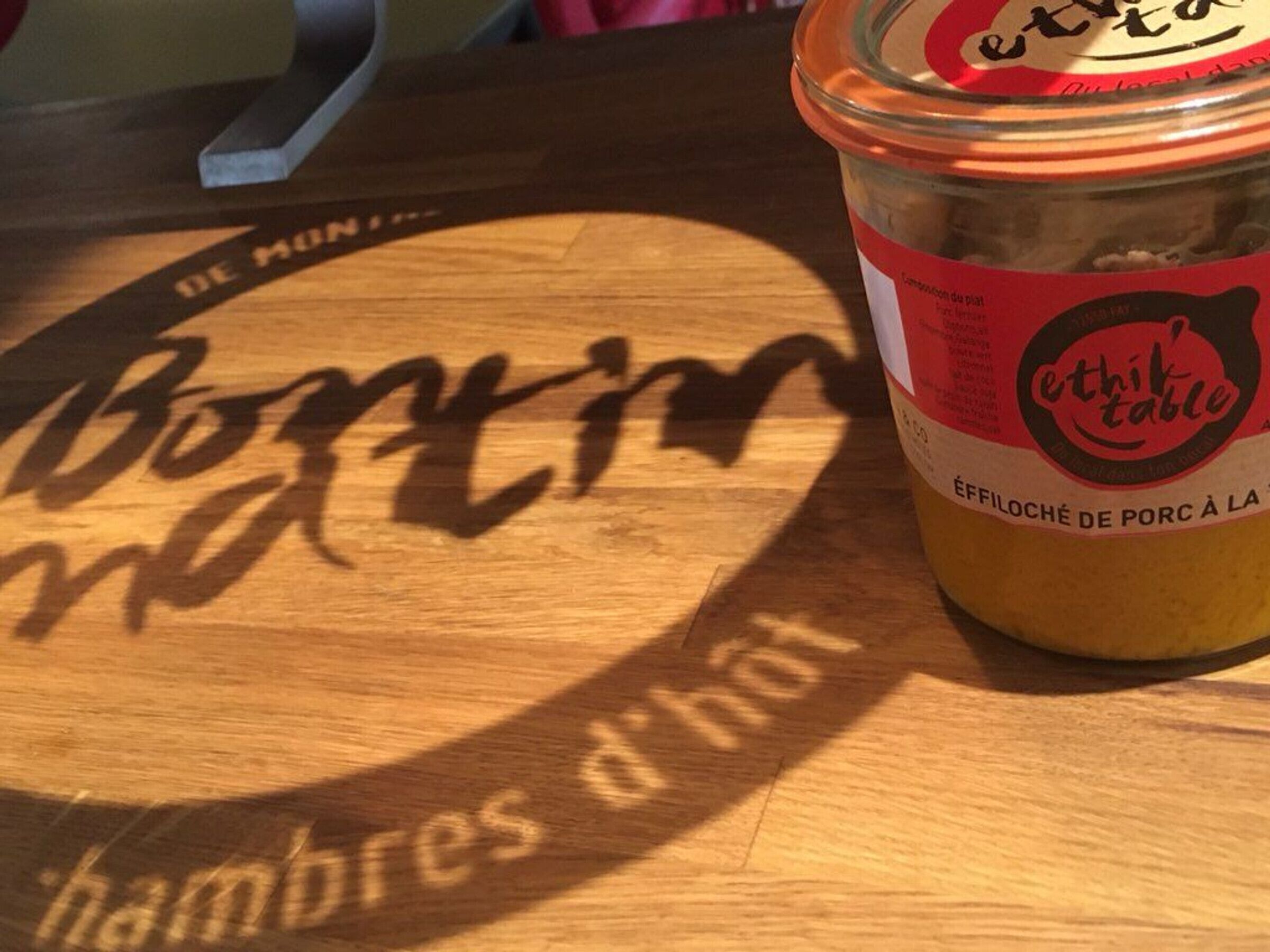 A wooden table with a logo and a jar of food.