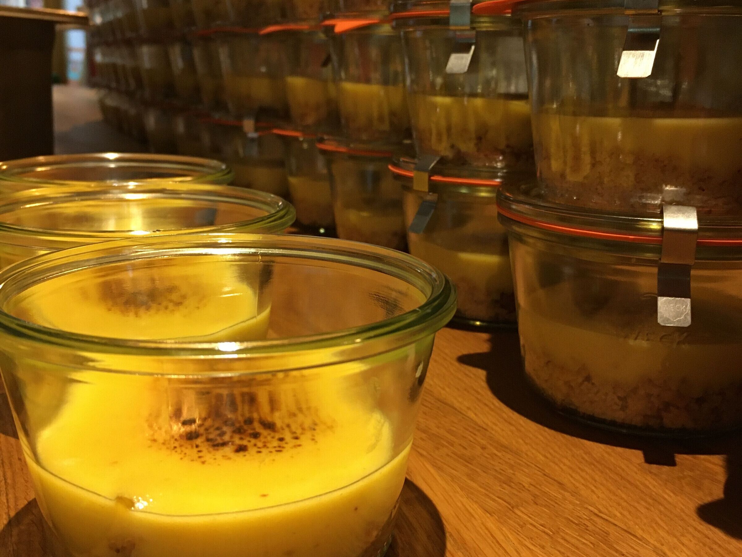 A row of glass jars with metal lids on a wooden surface.