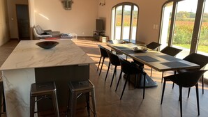 A modern kitchen with a large island, bar stools, and a dining area with chairs and a table.
