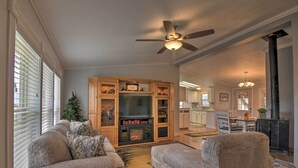 A living room with a fireplace, a ceiling fan, and a Christmas tree.