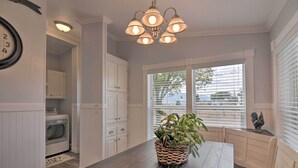A kitchen with a wooden table, white cabinets, a built-in oven, and a window with blinds.