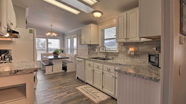 A modern kitchen with white cabinetry, granite countertops, and a central island.