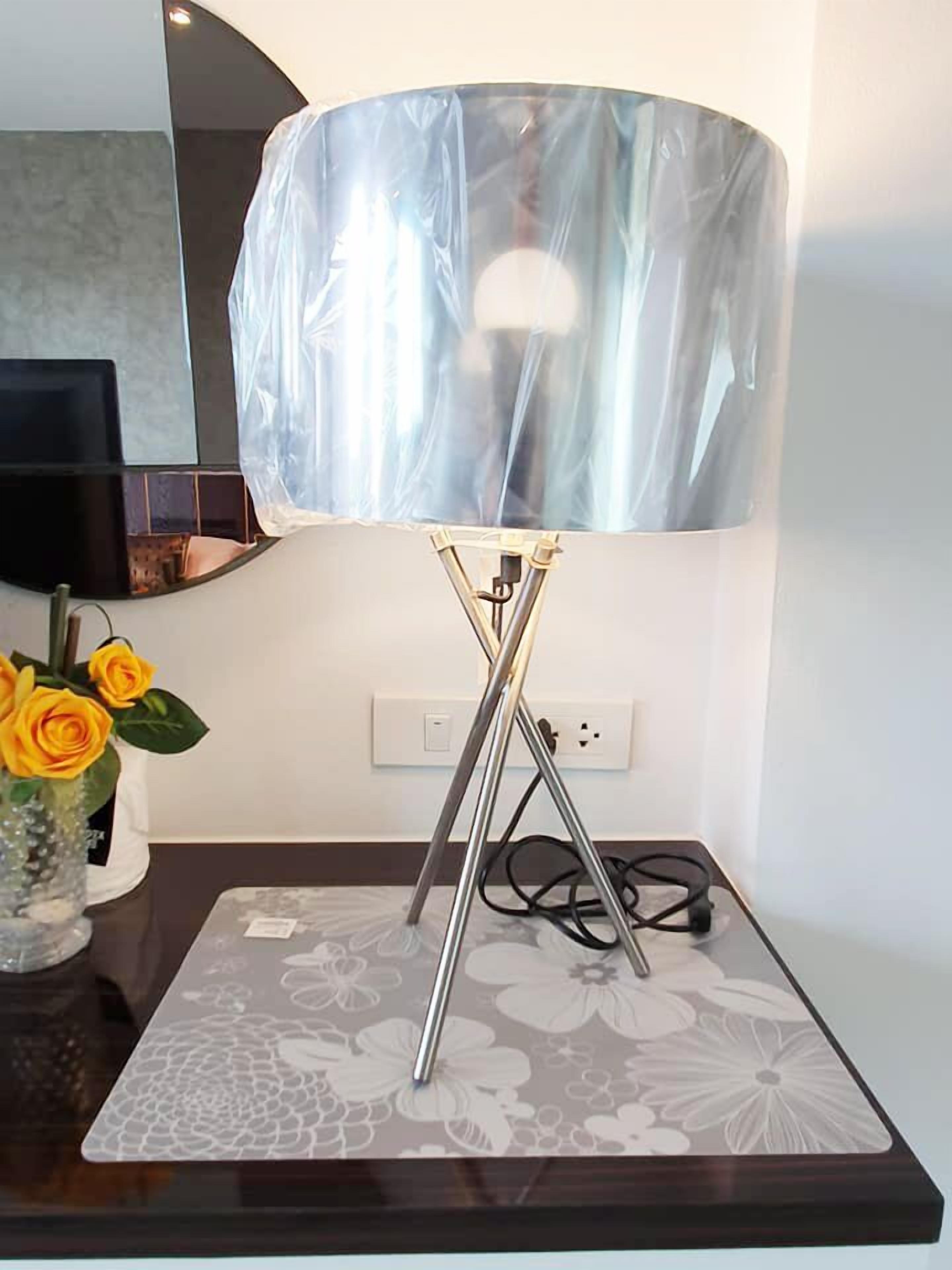 Una lampada moderna con un fusto metallico e un paralume ampio e traslucido su un tavolo.