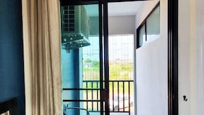 A room with a sliding glass door leading to a balcony with a metal chair and a small table. - Samutsakorn Apartment (Samut Sakhon)