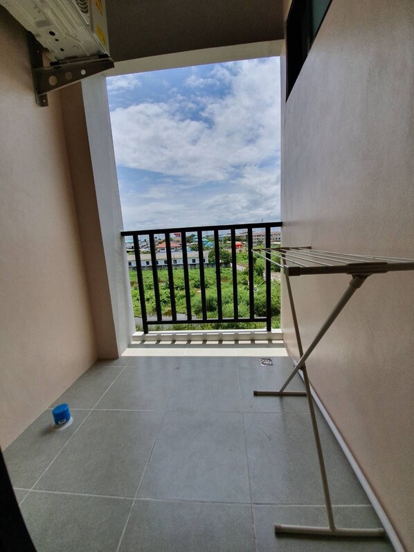 A balcony with a view of a green landscape and buildings.