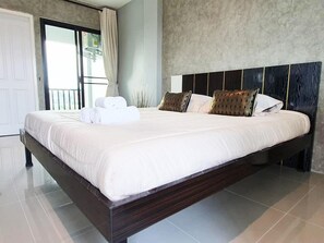 A large bed with white linens, a dark headboard, and two decorative pillows. - Samutsakorn Apartment (Samut Sakhon)