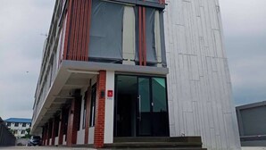A modern building with a glass facade, red vertical accents, and a brick base. - Samutsakorn Apartment (Samut Sakhon)