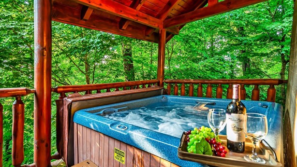 Een hottub met een houten terras, omringd door weelderig groen.