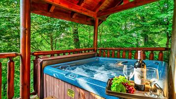 Un jacuzzi con terraza de madera, rodeado de exuberante vegetación.