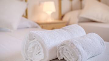 Un lit bien fait, avec des draps blancs et une serviette blanche enroulée posée sur le dessus.