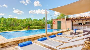 Un espace piscine avec des chaises longues et un coin salon abrité.
