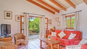 A living room with a television, wicker chairs, a red sofa, and a wooden coffee table. - Villa Joana with Mountain View, Wi-Fi, Garden, Pool & Terraces (Pollensa)
