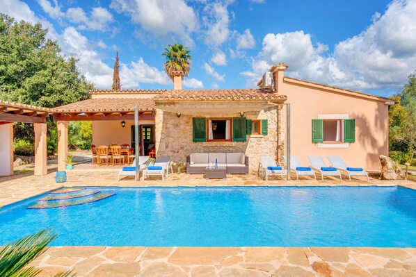 Una villa con piscina, mobiliario exterior y fachada de piedra.