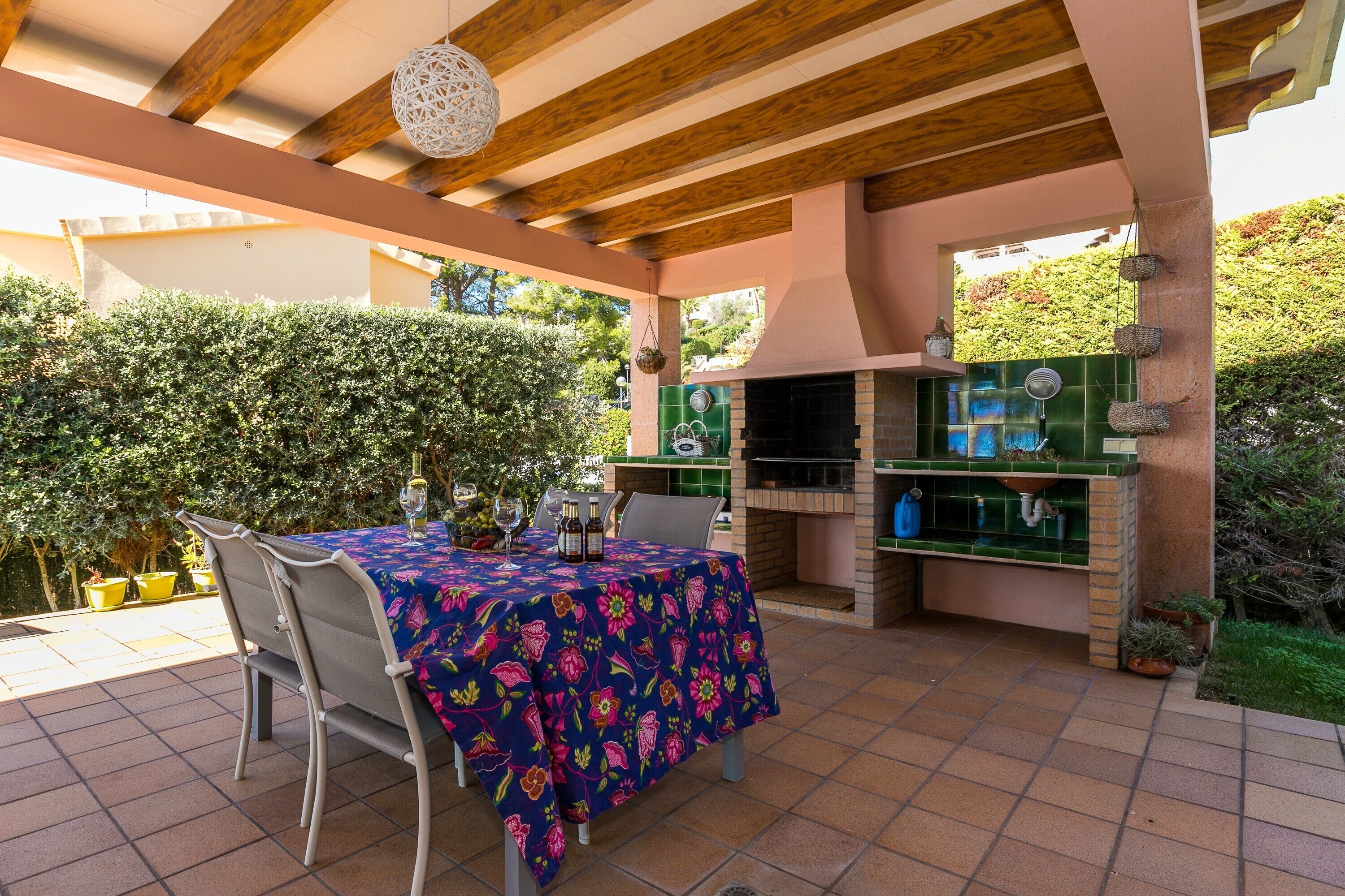 Un patio exterior con una mesa lista para comer, una parrilla y una planta en maceta.