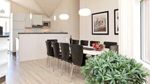 A modern kitchen with white cabinets, a black countertop, and a dining area with a white table and black chairs. - Holiday Home in GroÃŸenbrode (Grossenbrode)