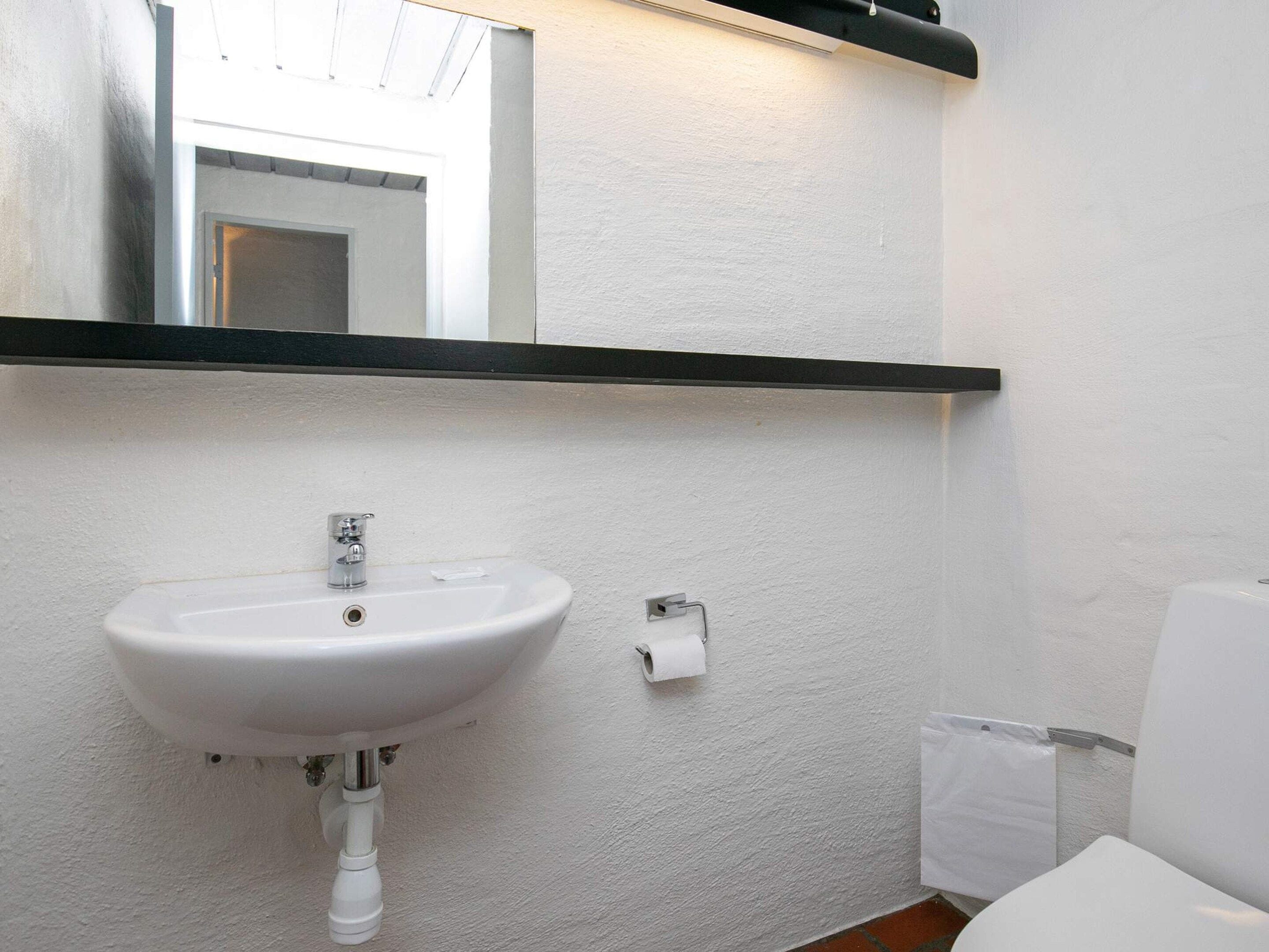 Ein Badezimmer mit einem weißen Waschbecken, einem Spiegel und einer Toilette.