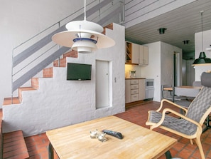 Interior moderno com escada, cozinha, área de jantar com mesa e cadeiras, e luminária pendente.