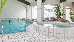 Piscina interna com piso em azulejo e área de hidromassagem.