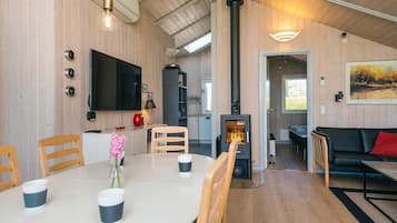 Et moderne interiør med spiseplads, opholdsstue og brændeovn.