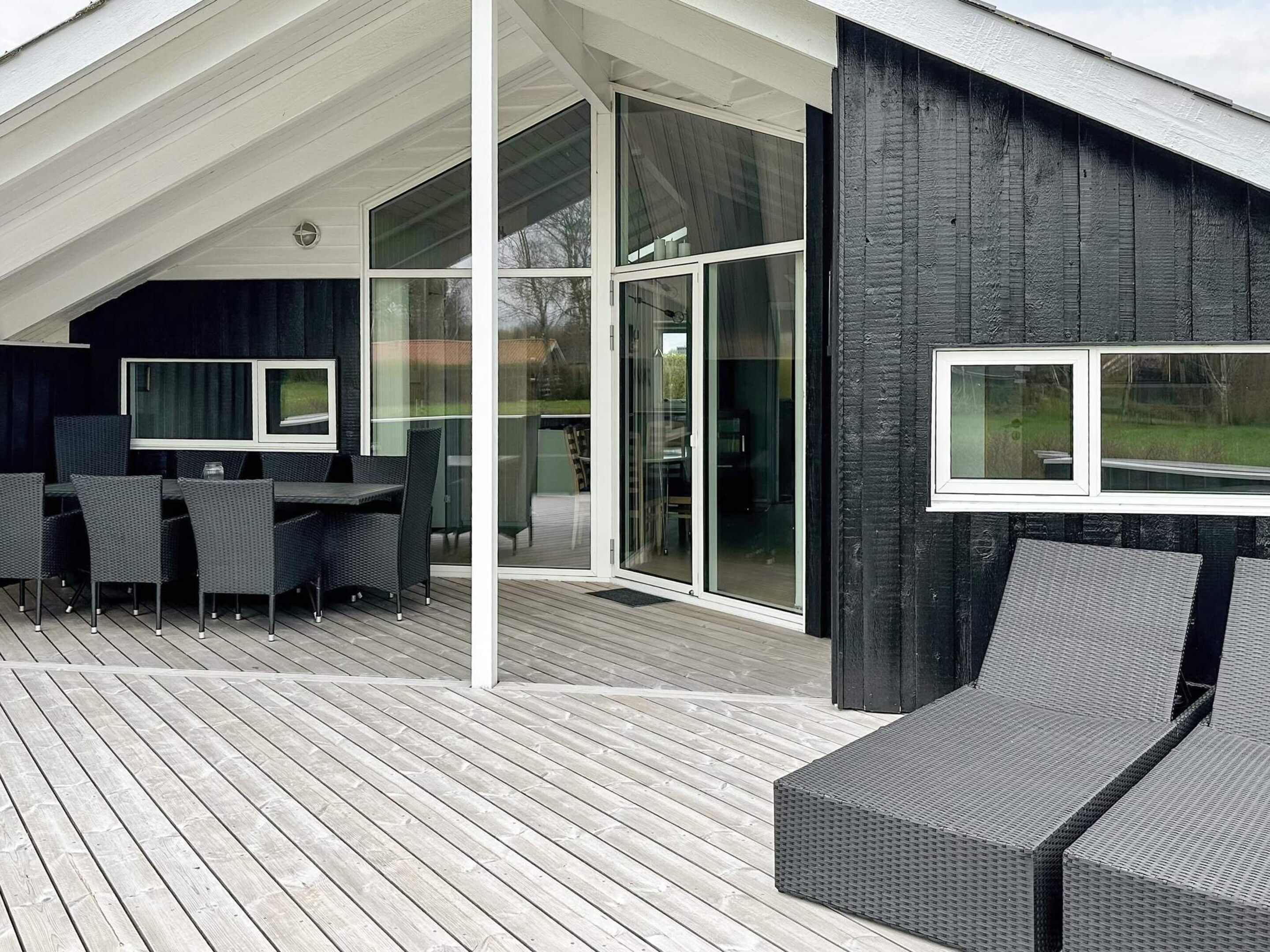 A modern outdoor deck with a dining area, large sliding glass doors, and a covered section.