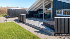 A modern house with a covered patio, outdoor seating, and a barbecue grill. - Holiday Home in Sydals (Sydals)