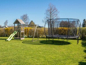 A playground with a swing set, slide, and trampoline. - Holiday Home in Sydals (Sydals)