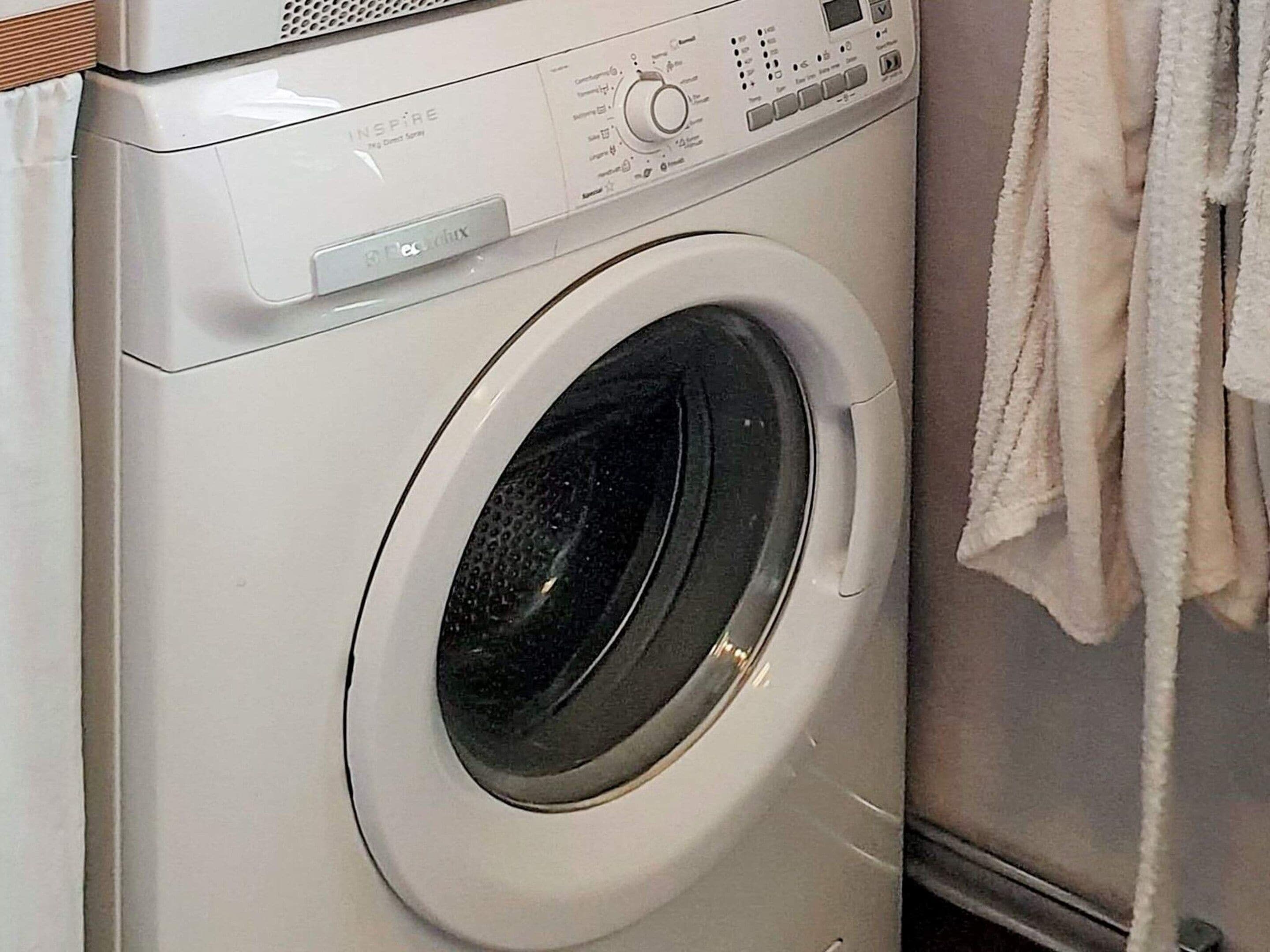 Een wasmachine met voorlader, bedieningspaneel en een handdoek aan de rechterkant.