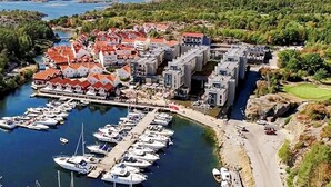 Una marina con imbarcazioni ormeggiate, un campo da golf e edifici residenziali con tetti rossi.