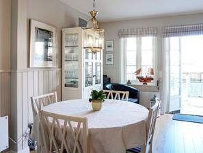 A dining area with a round table, chairs, a chandelier, a cabinet with glassware, and a view of the outside. - 4 Star Holiday Home in Stromstad (Stromstad)
