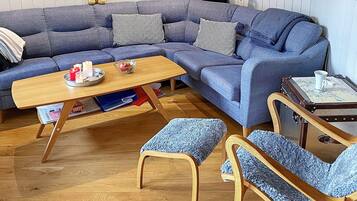Una sala de estar moderna con un sofá azul, una mesa de centro de madera y sillones a juego.